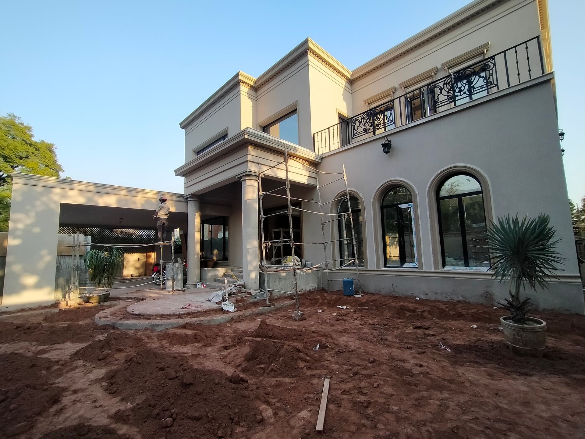 A large house under construction with scaffolding and unfinished landscaping.